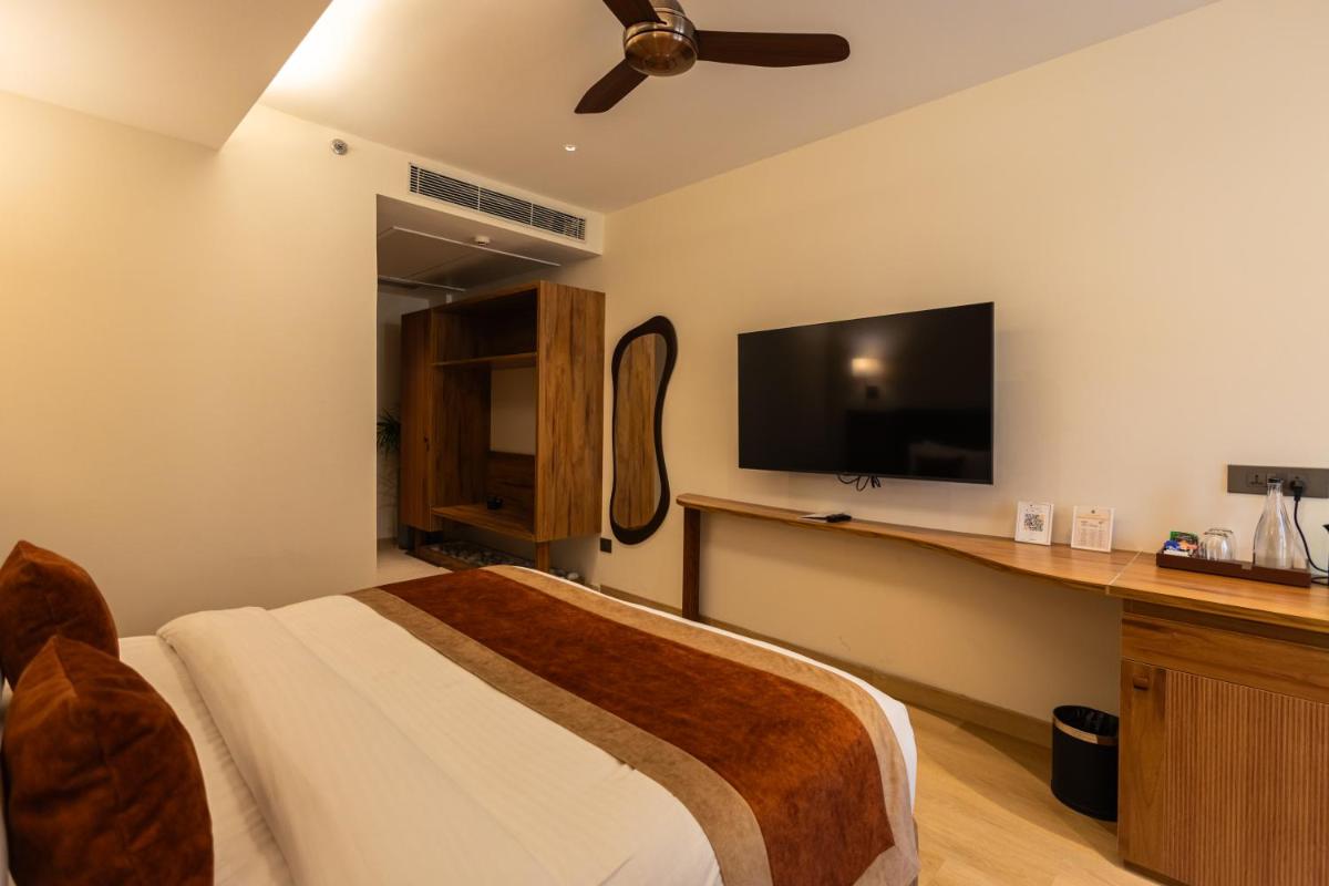 a bedroom with a bed and a flat screen tv at Antalya By Divine Ganga Cottage in Rishīkesh
