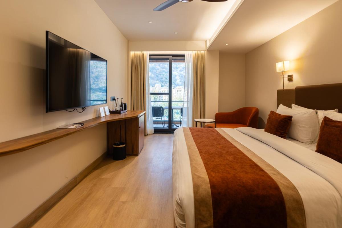 a hotel room with a bed and a flat screen tv at Antalya By Divine Ganga Cottage in Rishīkesh
