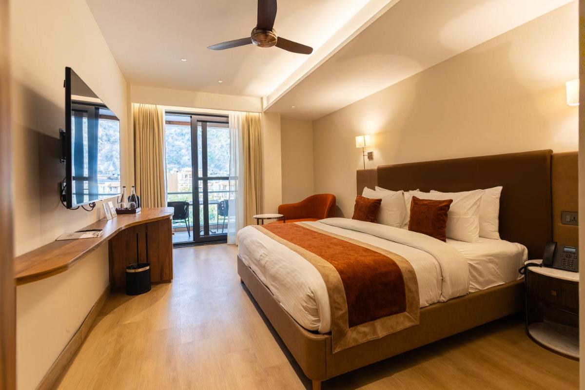 a hotel room with a bed and a television at Antalya By Divine Ganga Cottage in Rishīkesh