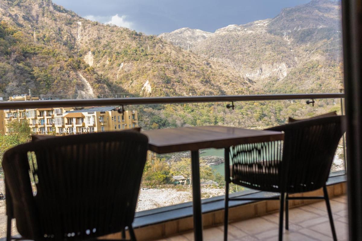 a table and chairs on a balcony with mountains at Antalya By Divine Ganga Cottage in Rishīkesh