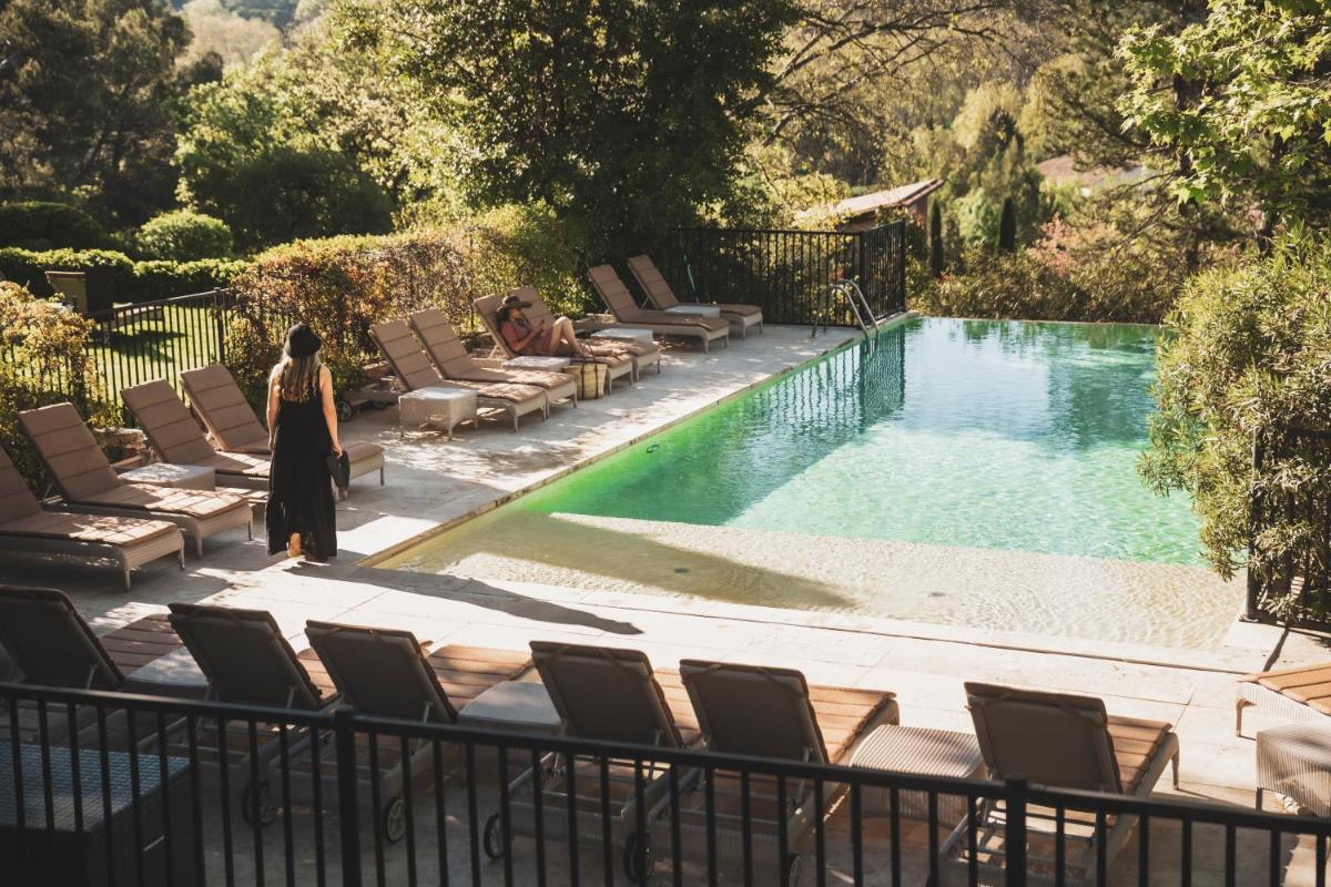une femme debout à côté d'une piscine avec des chaises dans l'établissement Les Lodges Sainte-Victoire Hotel & Spa, à Aix-en-Provence