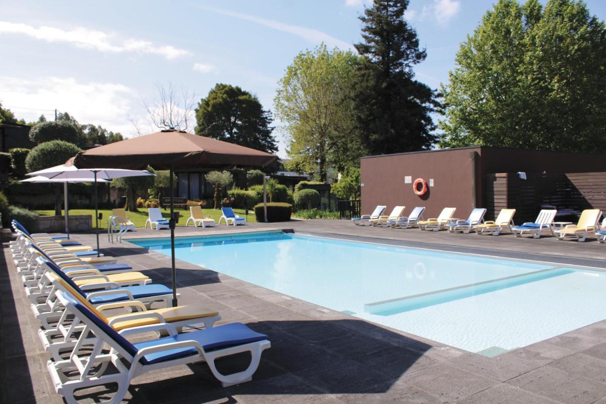 uma piscina com espreguiçadeiras e um guarda-sol em Prazer da Natureza Resort & Spa em Caminha