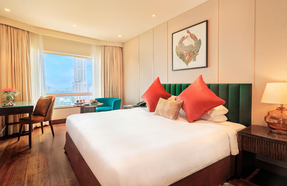 a hotel room with a large bed with red pillows at President - IHCL SeleQtions in Mumbai