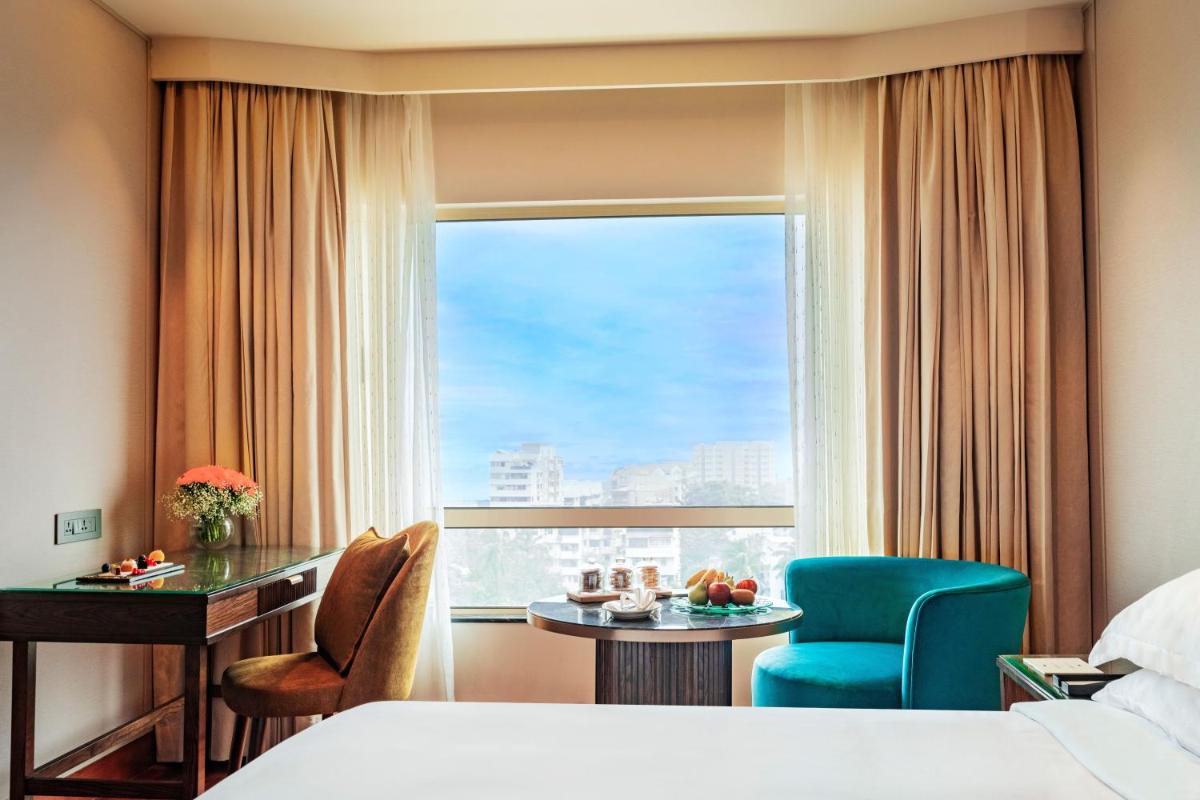 a hotel room with a bed and a desk and a window at President - IHCL SeleQtions in Mumbai