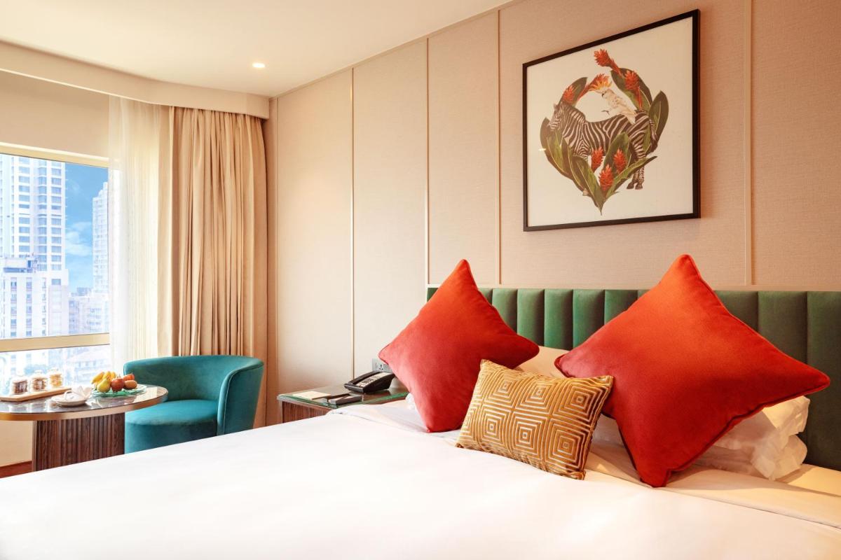 a hotel room with a bed with red pillows at President - IHCL SeleQtions in Mumbai