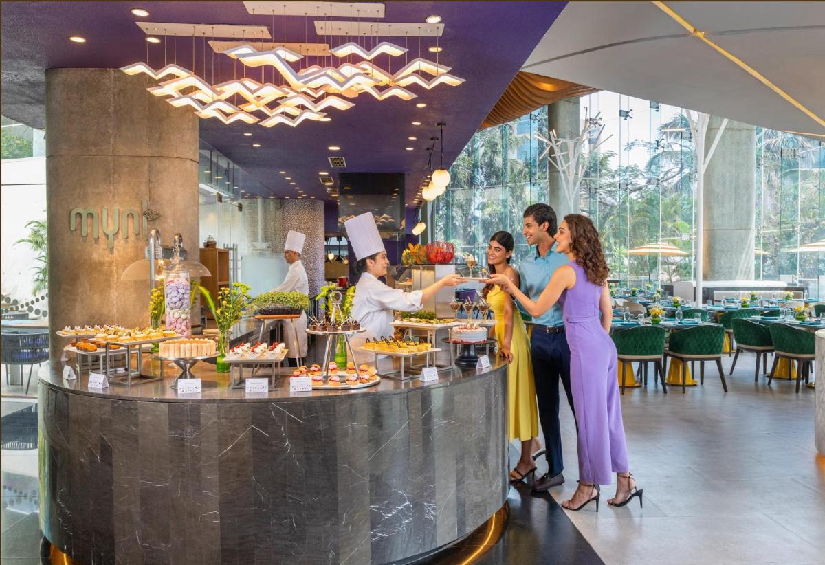 a group of people standing around a food counter at Vivanta Bengaluru, Whitefield in Bengaluru
