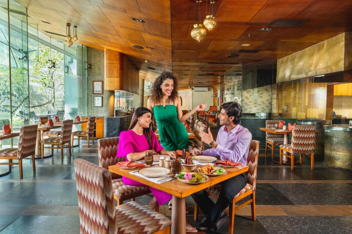 a woman standing at a table in a restaurant at Vivanta Bengaluru, Whitefield in Bengaluru