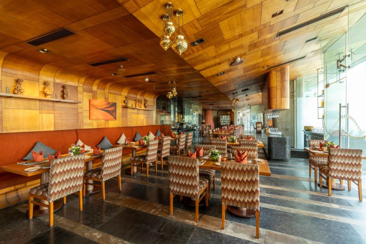 a restaurant with wooden walls and tables and chairs at Vivanta Bengaluru, Whitefield in Bengaluru