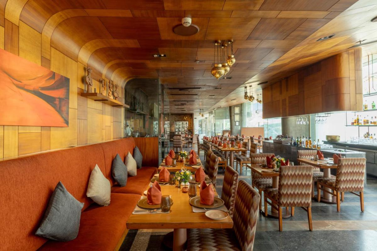 a dining room with wooden tables and chairs at Vivanta Bengaluru, Whitefield in Bengaluru