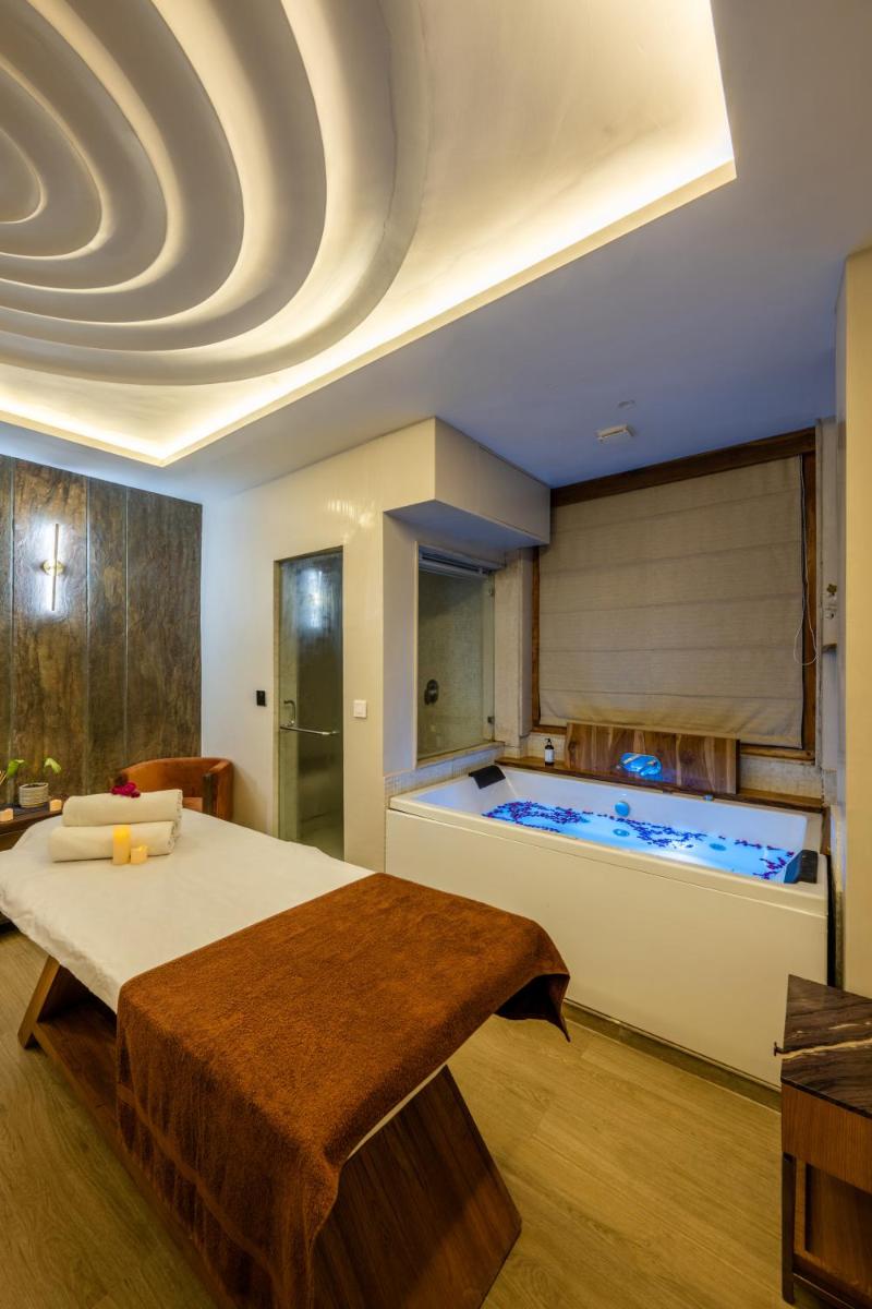a bedroom with a large bed and a tub at Antalya By Divine Ganga Cottage in Rishīkesh