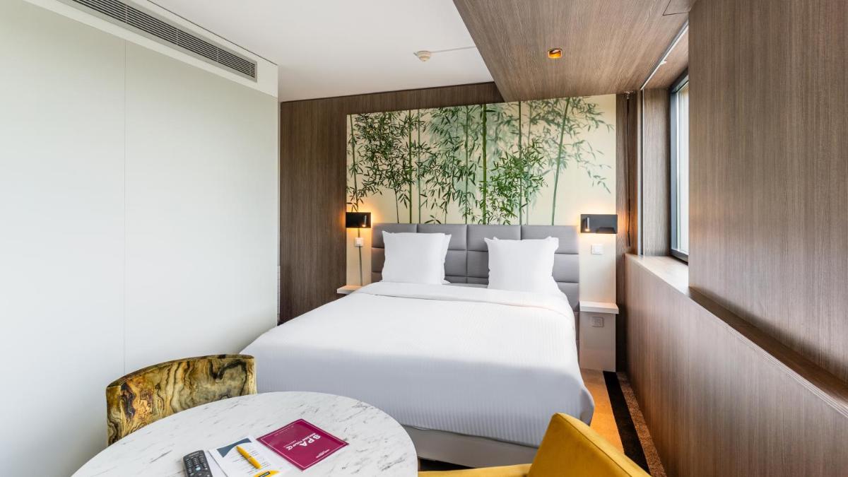 une chambre d'hôtel avec un lit et une table dans l'établissement Golden Tulip Amnéville - Hôtel Spa & Casino, à Amnéville