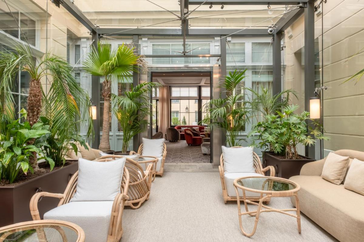 un hall d'entrée de bureau avec des chaises et des plantes dans l'établissement Hôtel Les Lumières - Relais & Châteaux, à Versailles