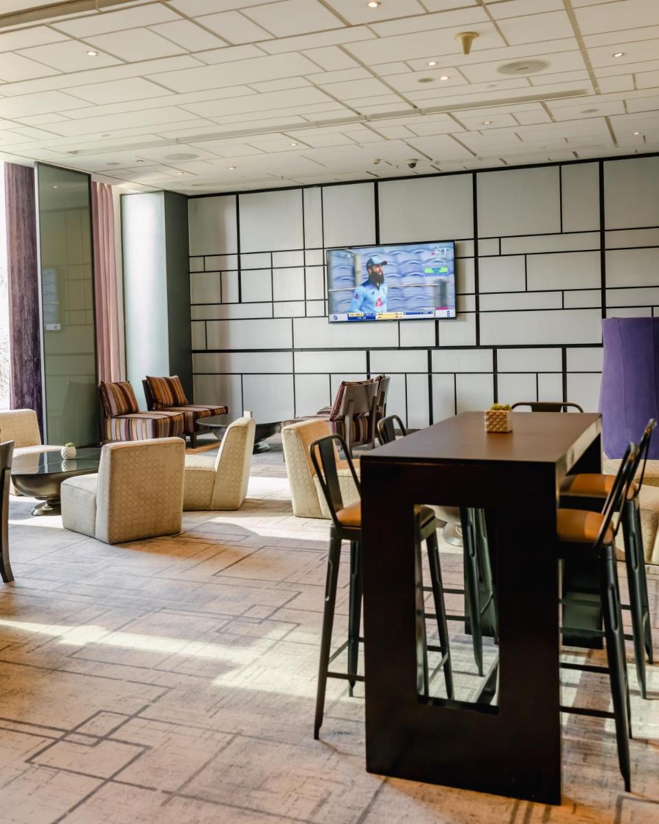 a lobby with chairs and a table and a tv at Hyatt Regency Gurgaon in Gurgaon