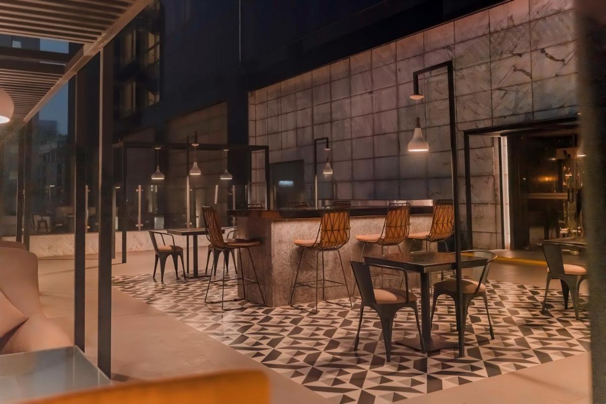 a restaurant with a bar with chairs and tables at Hyatt Regency Gurgaon in Gurgaon