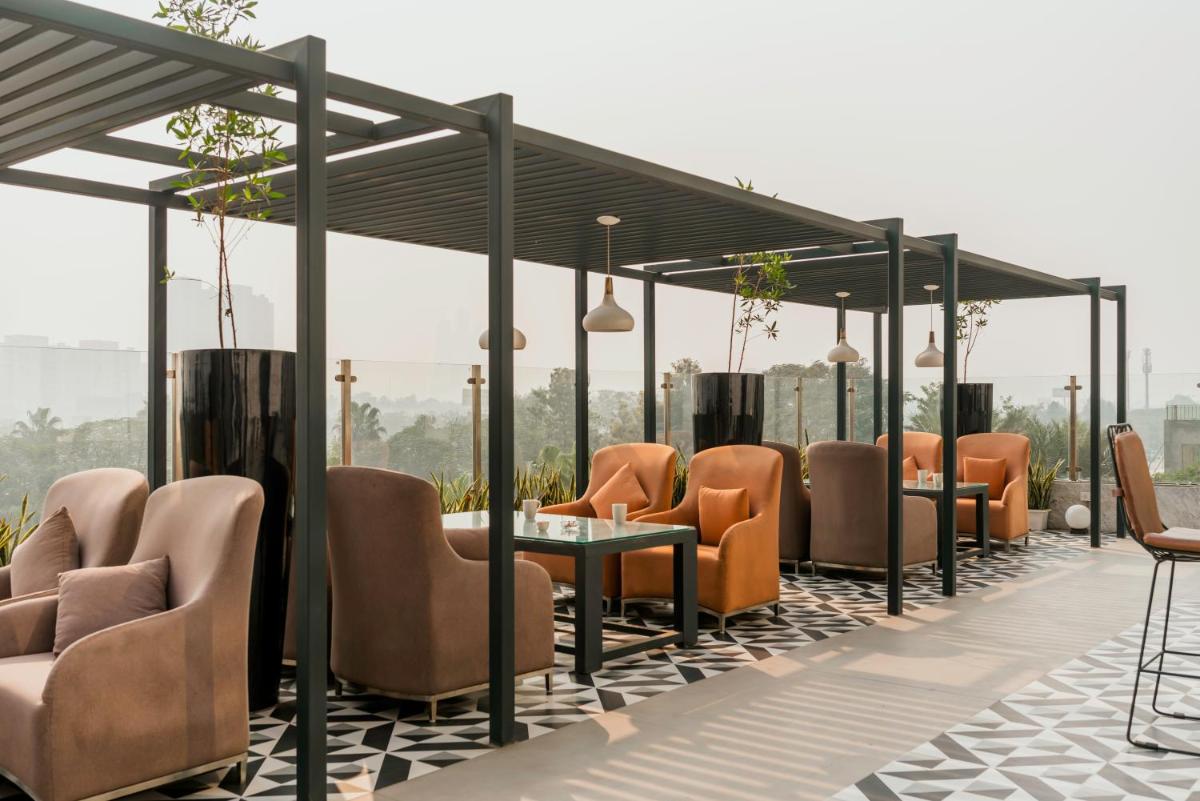 a restaurant with orange chairs and tables on a roof at Hyatt Regency Gurgaon in Gurgaon