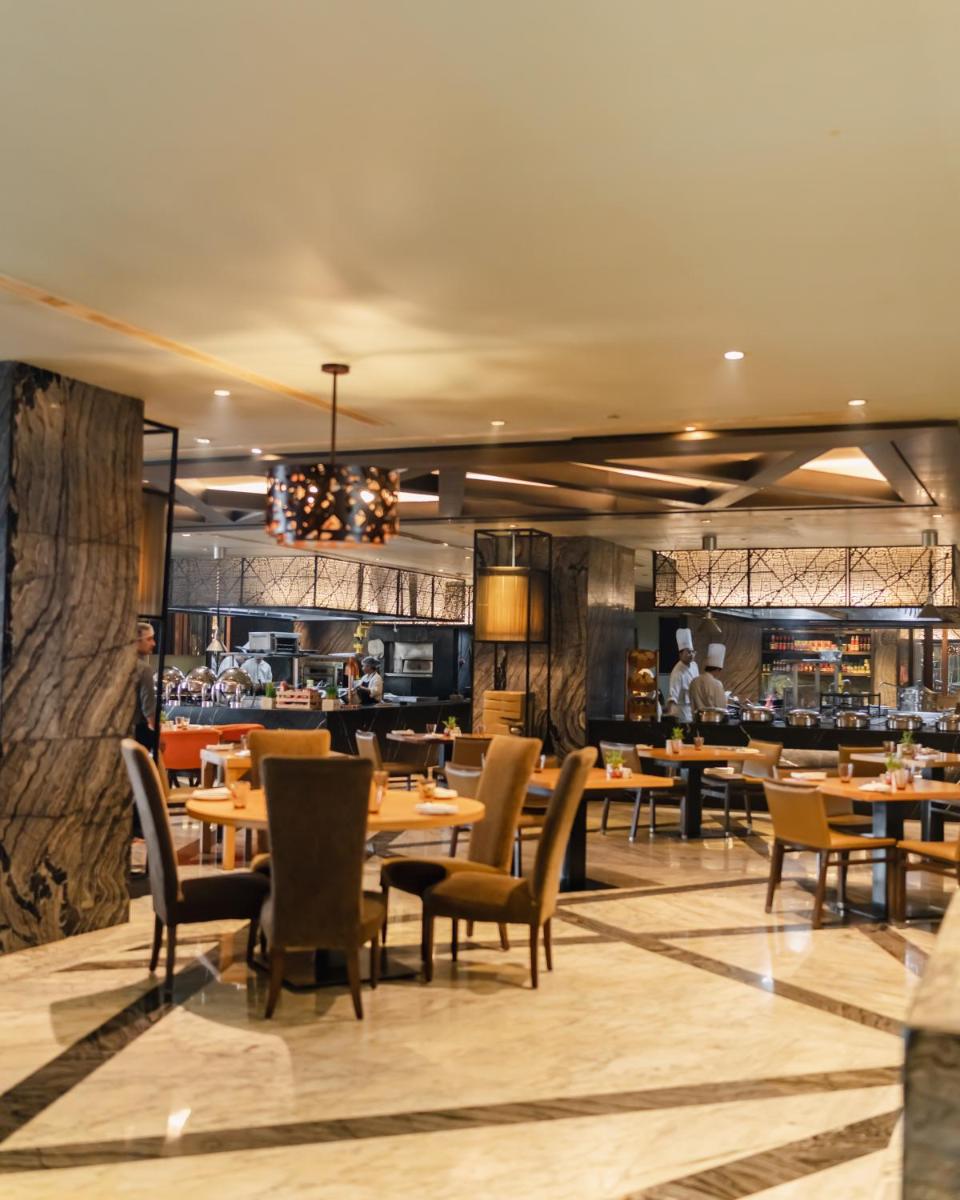 a restaurant with tables and chairs and a bar at Hyatt Regency Gurgaon in Gurgaon