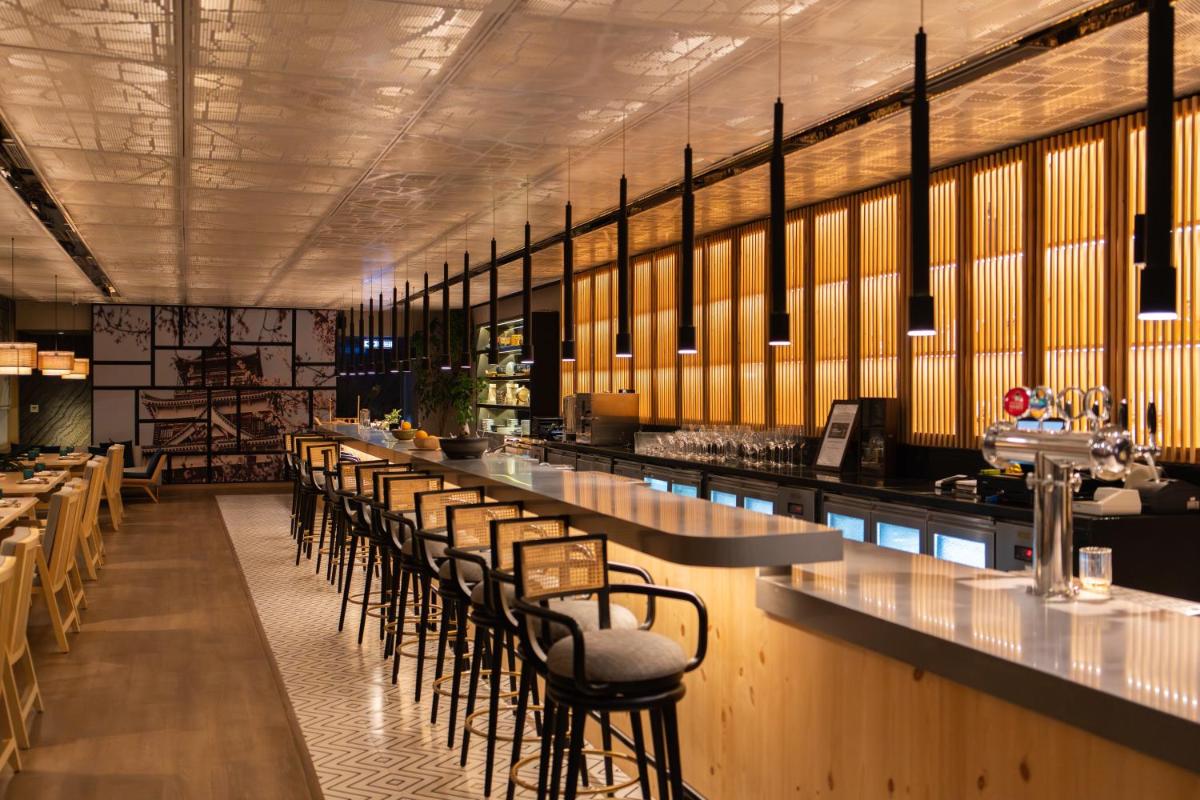 a restaurant with a long bar with stools at Hyatt Regency Gurgaon in Gurgaon