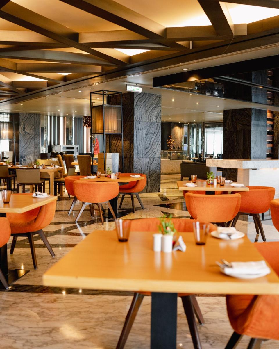 a restaurant with wooden tables and chairs at Hyatt Regency Gurgaon in Gurgaon