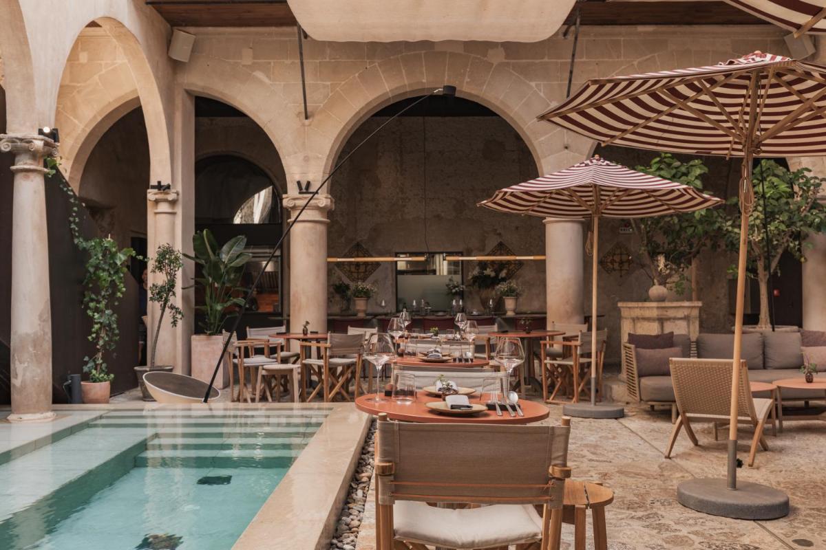 un restaurante con piscina, mesas y sombrillas en Nobis Hotel Palma, a Member of Design Hotels, en Palma de Mallorca