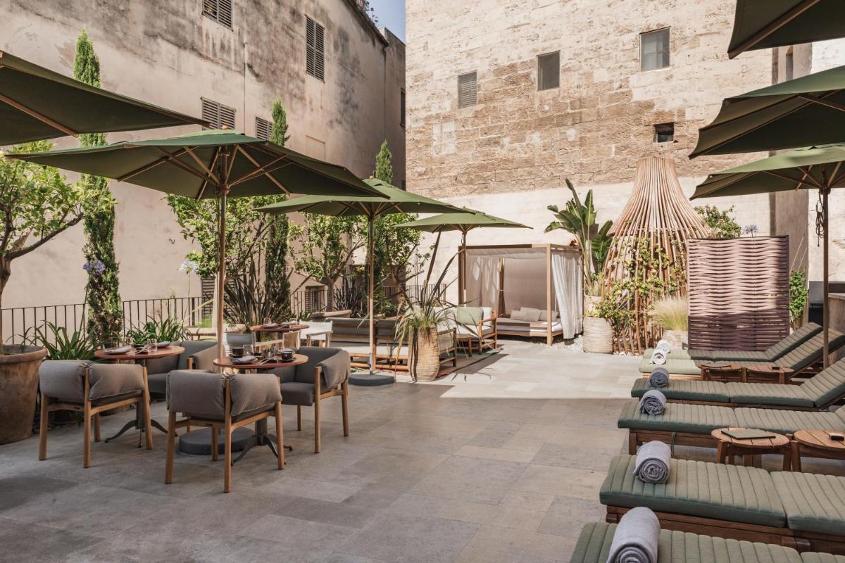 Un patio con mesas, sillas y sombrillas. en Nobis Hotel Palma, a Member of Design Hotels, en Palma de Mallorca