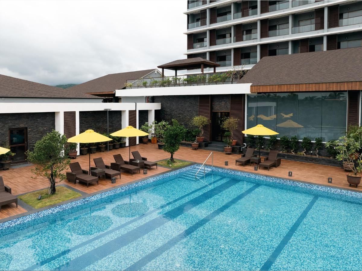 a swimming pool with chairs and umbrellas next to a building at Gateway Goa, Palolem in Palolem