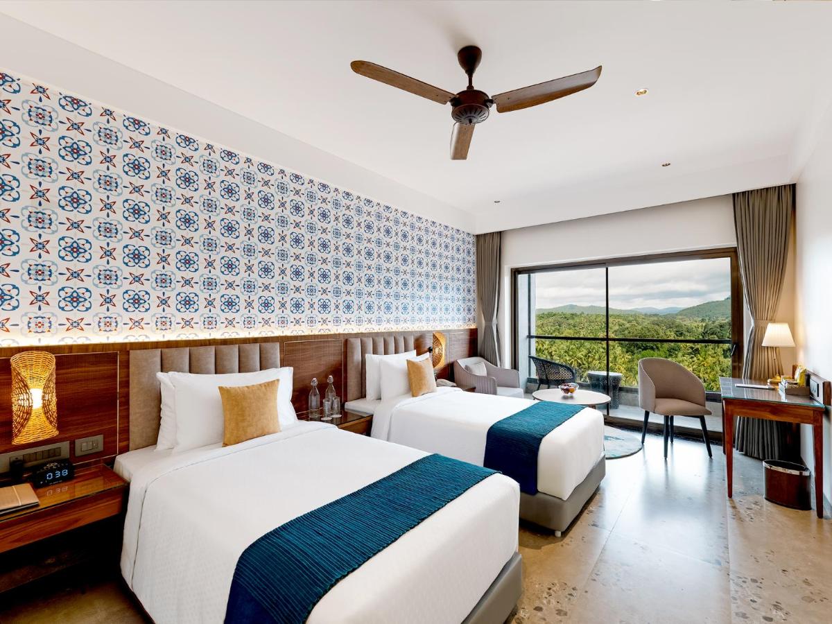 two beds in a hotel room with a ceiling fan at Gateway Goa, Palolem in Palolem