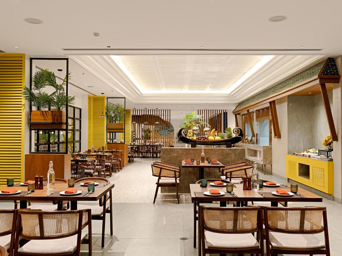 a restaurant with wooden tables and chairs and yellow walls at Gateway Goa, Palolem in Palolem