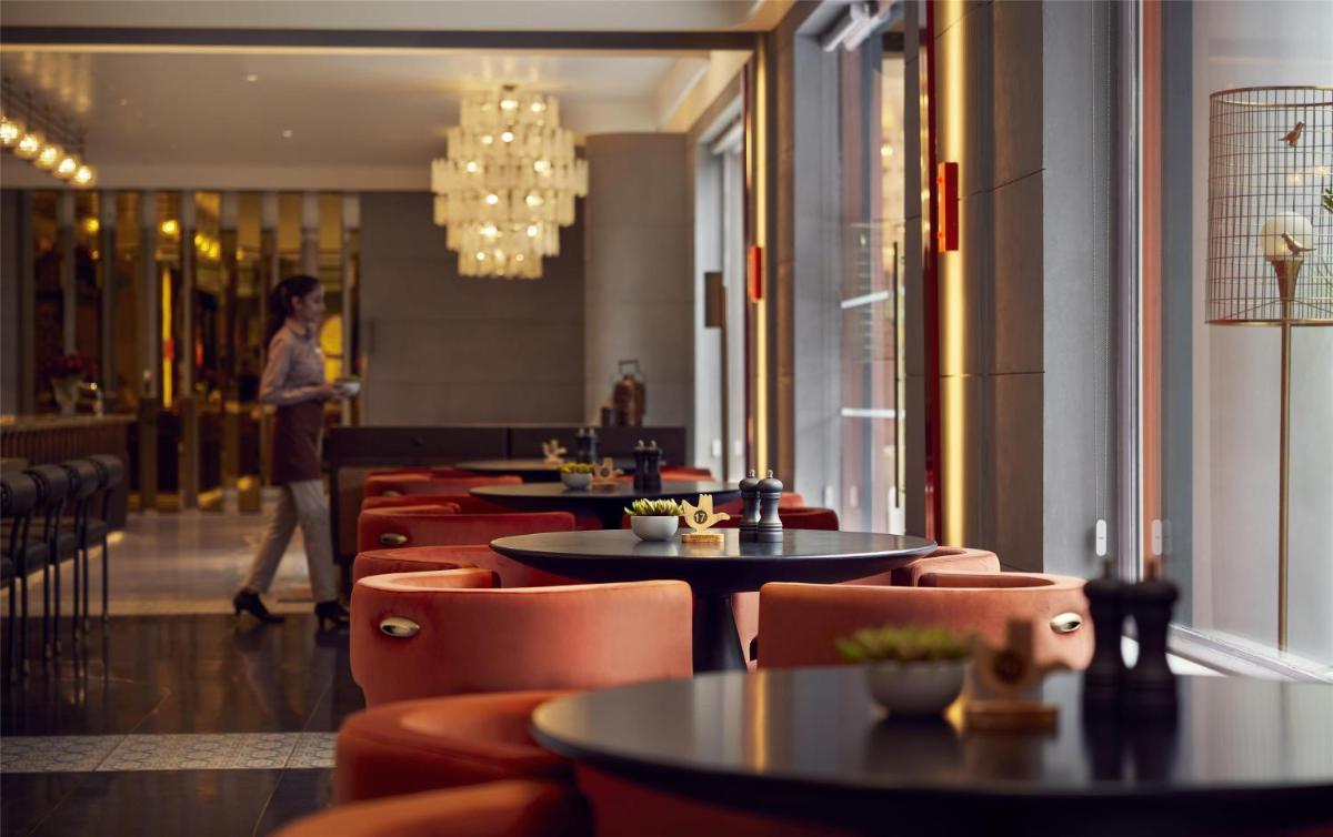 a restaurant with tables and chairs and a person walking in the background at Hyatt Centric Sector17 Chandigarh in Chandīgarh