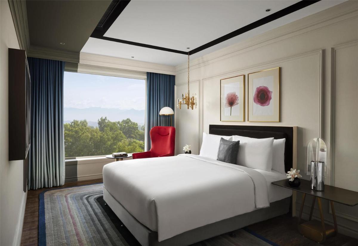 a bedroom with a large white bed and a red chair at Hyatt Centric Sector17 Chandigarh in Chandīgarh