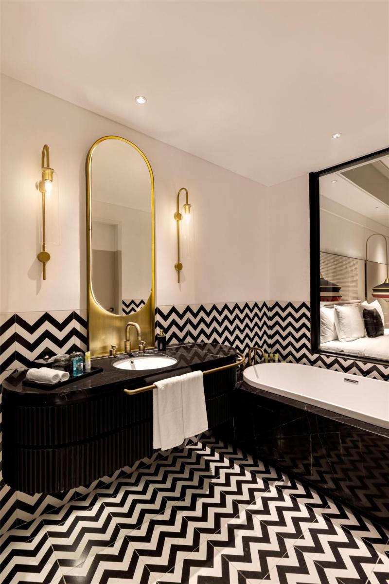 a bathroom with a sink and a mirror and a bed at Hyatt Centric Sector17 Chandigarh in Chandīgarh
