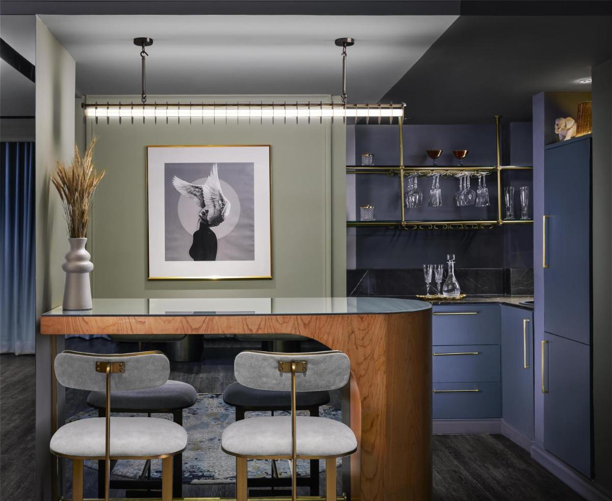 a kitchen with blue cabinets and a counter with stools at Hyatt Centric Sector17 Chandigarh in Chandīgarh