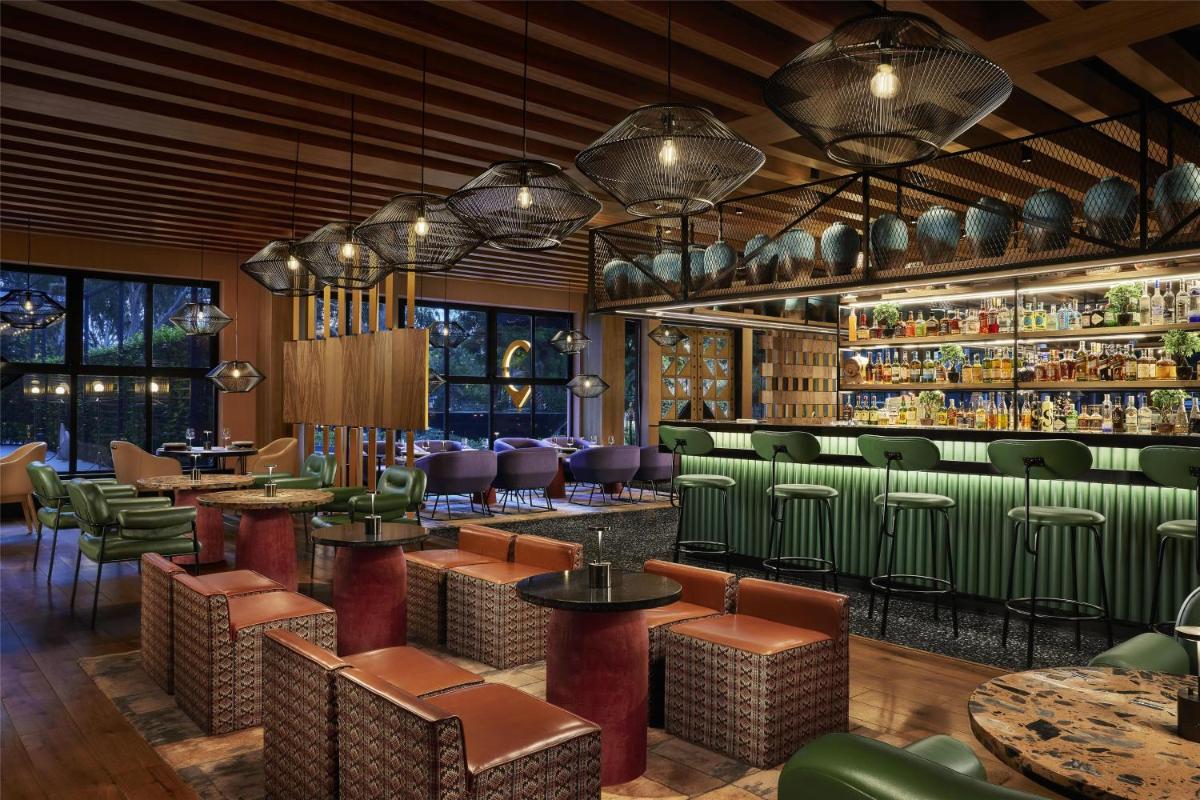 a restaurant with green chairs and tables and a bar at Hyatt Centric Sector17 Chandigarh in Chandīgarh