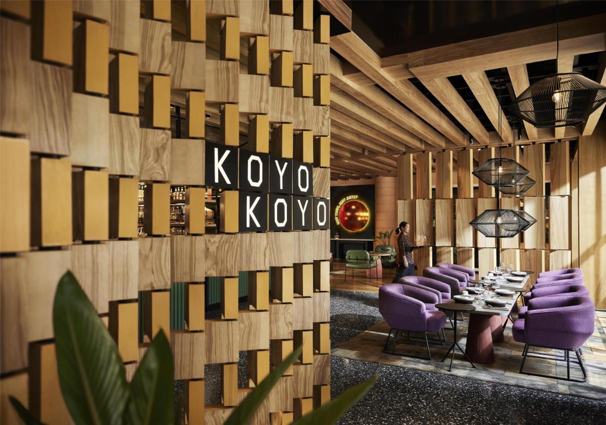 a restaurant with purple chairs and a wall of wood at Hyatt Centric Sector17 Chandigarh in Chandīgarh