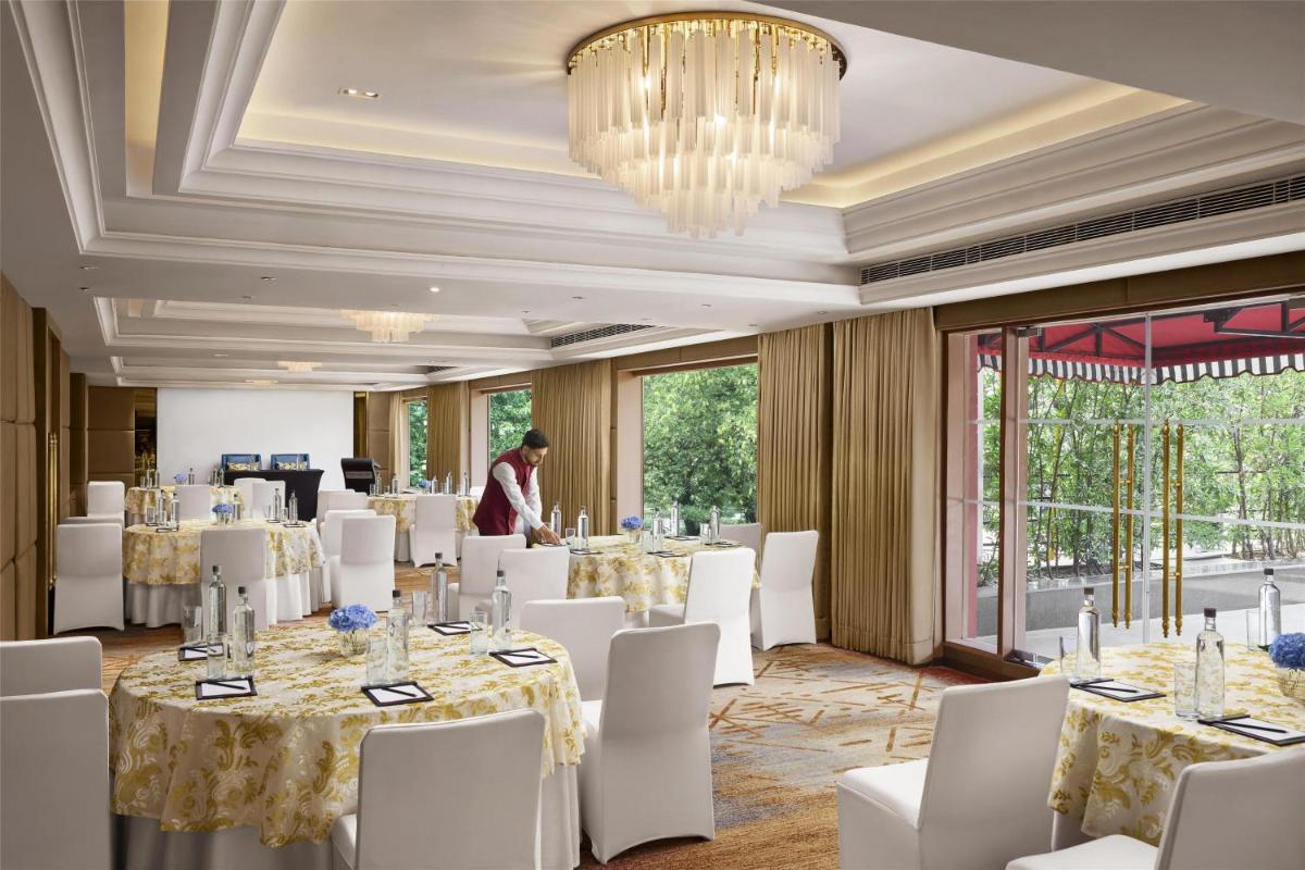 a room with tables and white chairs and a chandelier at Hyatt Centric Sector17 Chandigarh in Chandīgarh