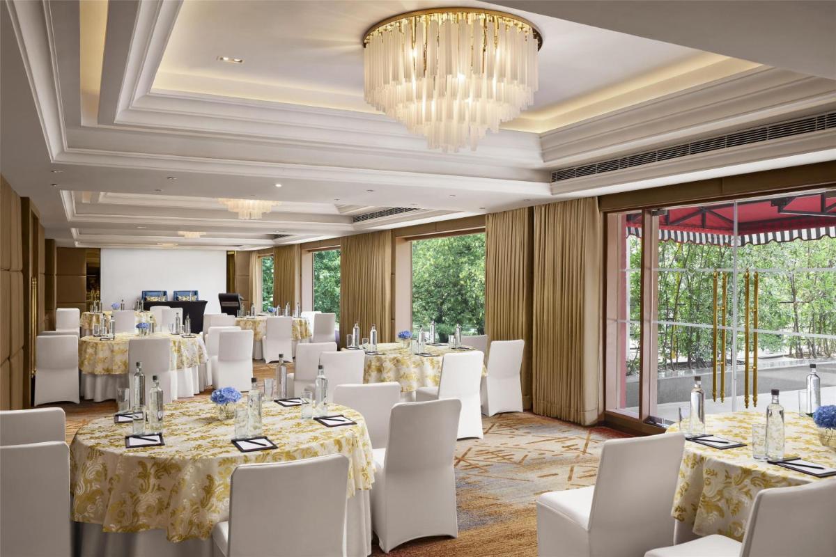a ballroom with tables and white chairs and a chandelier at Hyatt Centric Sector17 Chandigarh in Chandīgarh