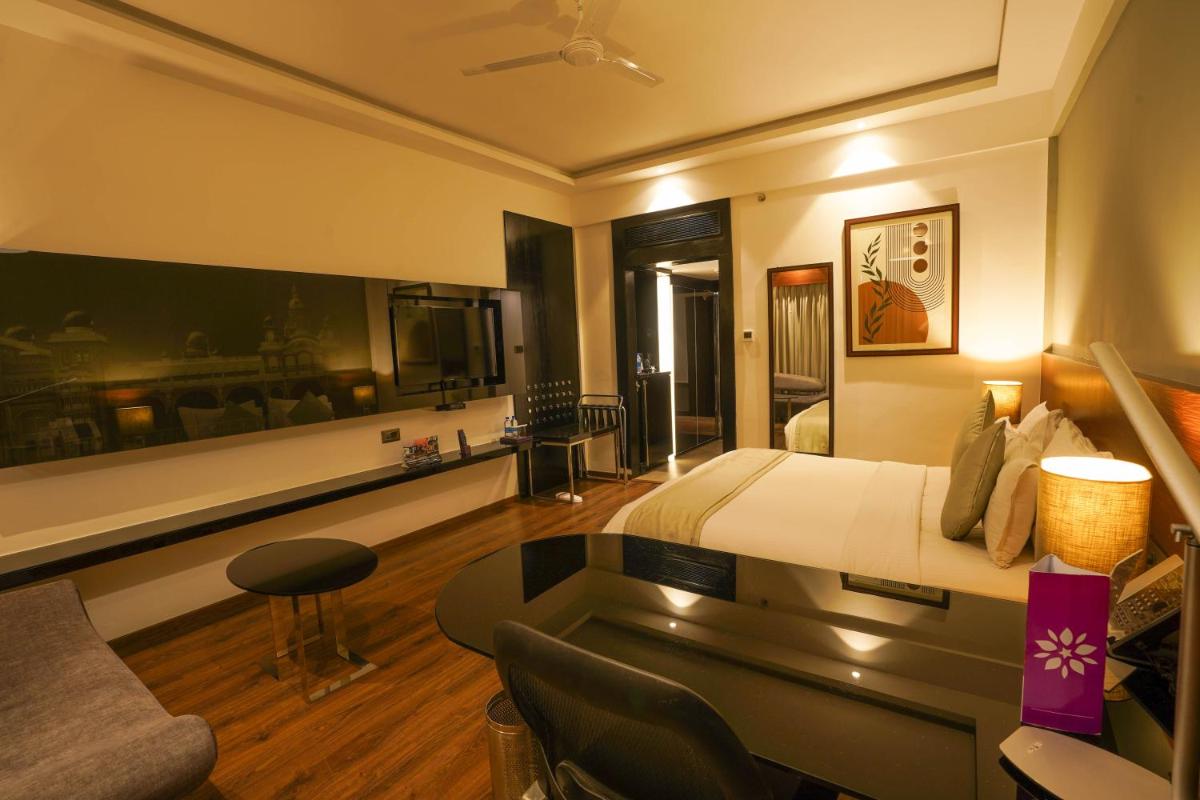 a hotel room with a bed and a living room at Southern Star,Mysore in Mysore