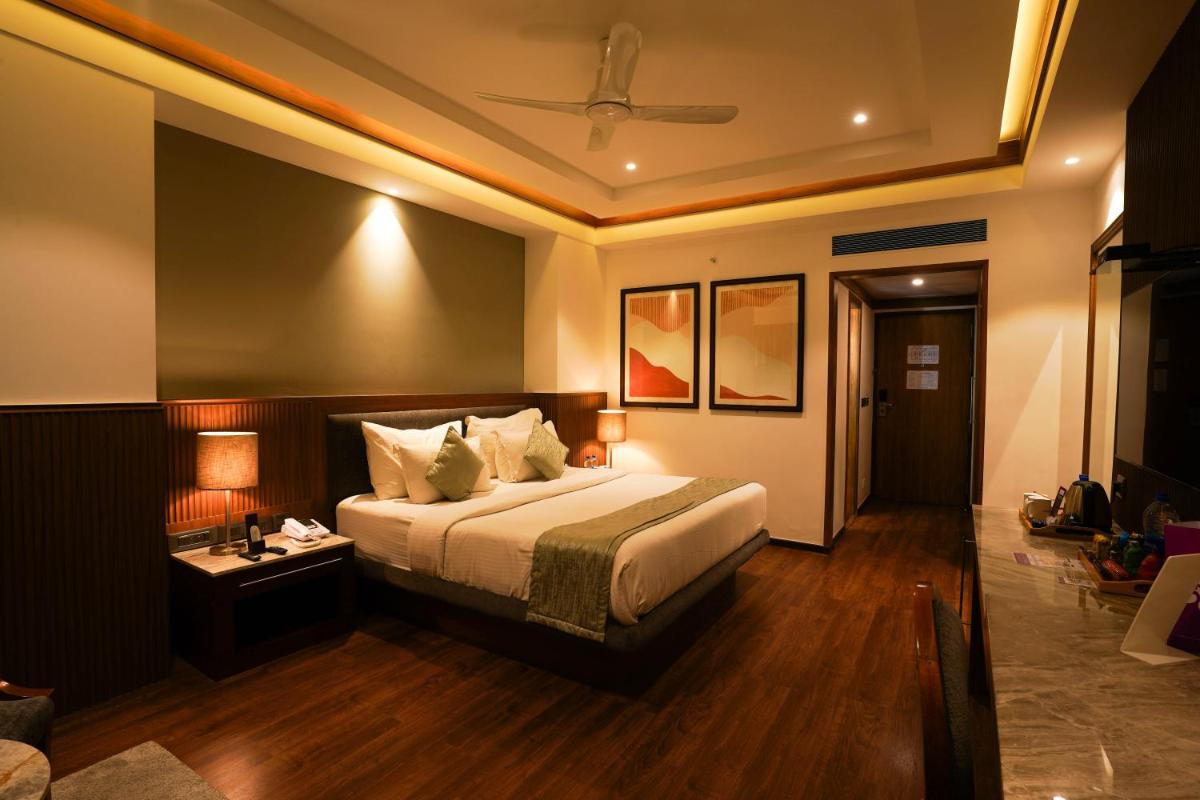 a bedroom with a bed and a table with a lamp at Southern Star,Mysore in Mysore