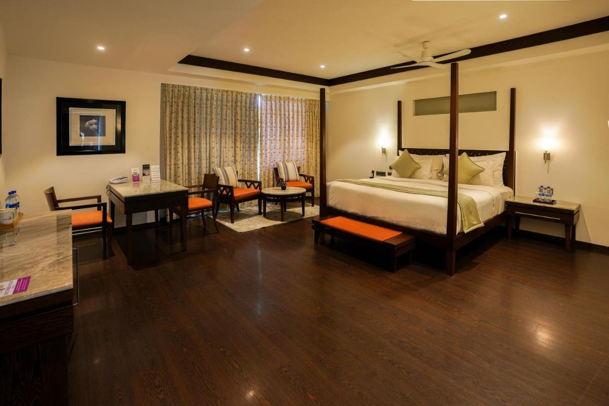 a hotel room with a bed and a dining room at Southern Star,Mysore in Mysore
