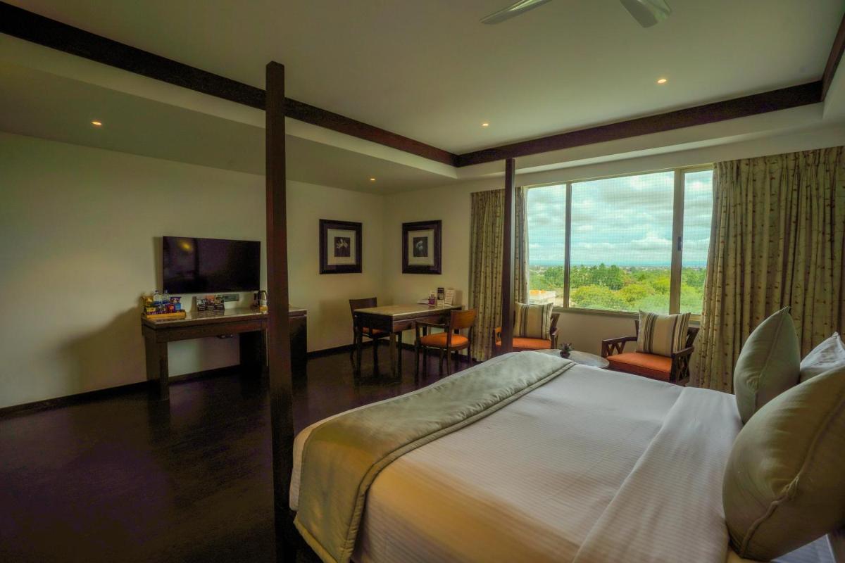 a hotel room with a bed and a desk and a television at Southern Star,Mysore in Mysore