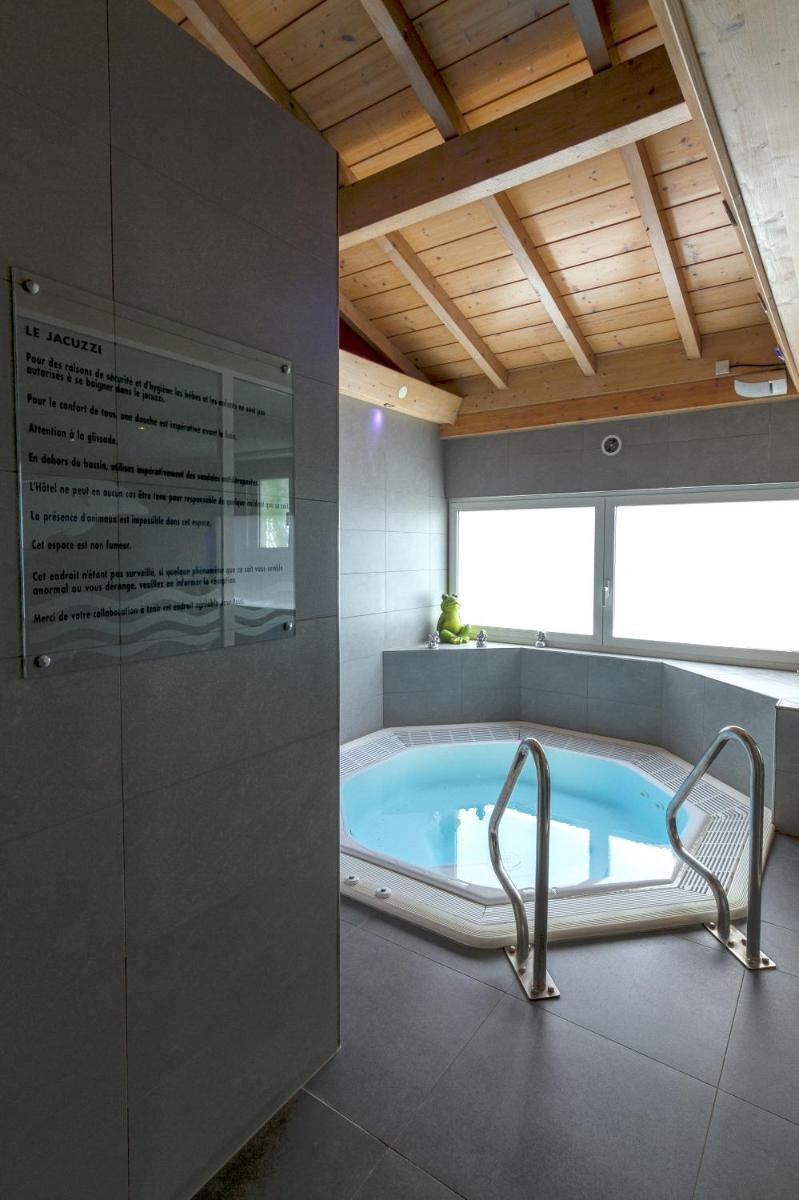 La salle de bains est pourvue d'une baignoire avec une chaise. dans l'établissement Hôtel Restaurant et Spa Au Tilleul, à Labaroche