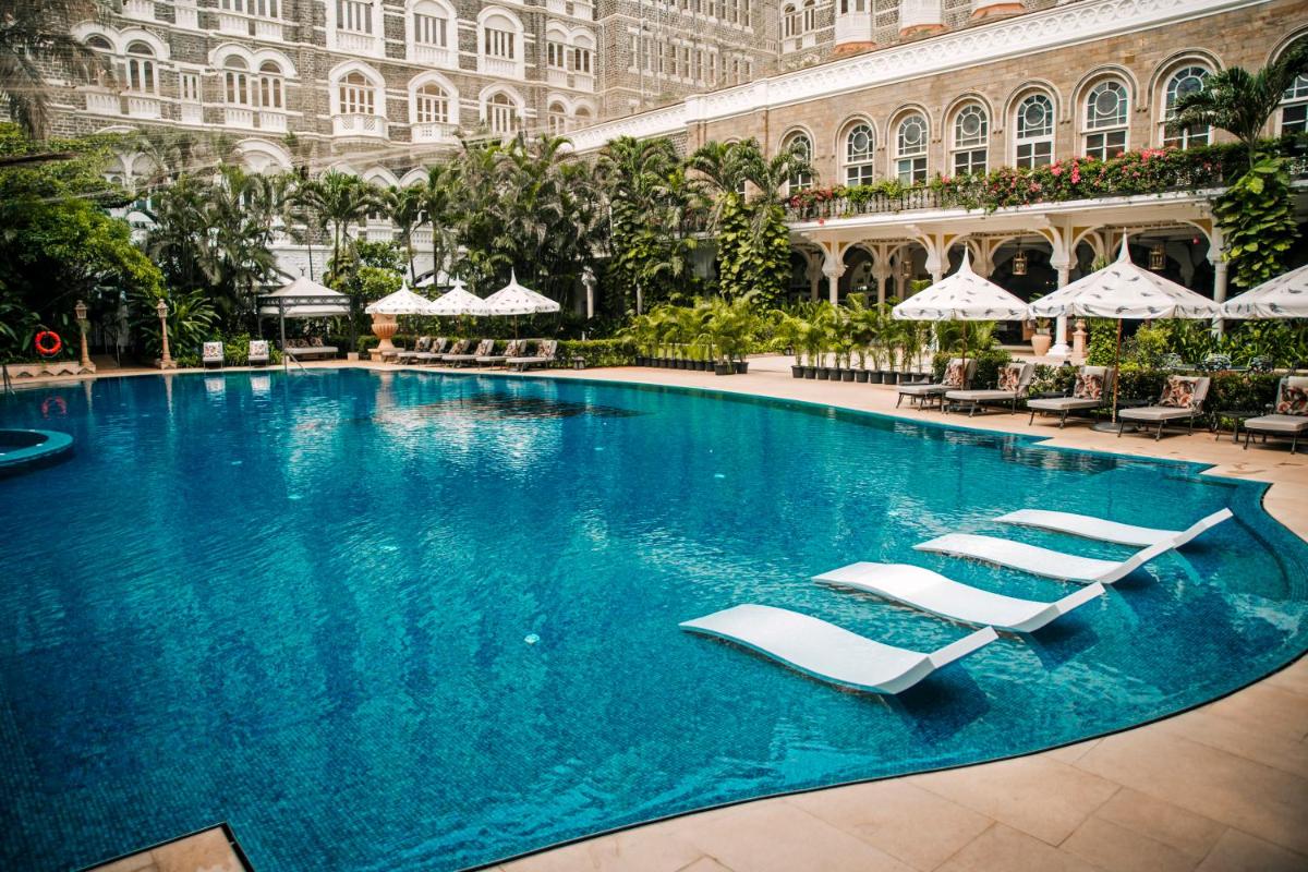a large swimming pool in a building with lounge chairs at The Taj Mahal Tower, Mumbai in Mumbai a large swimming pool in a building with lounge chairs at The Taj Mahal Tower, Mumbai in Mumbai