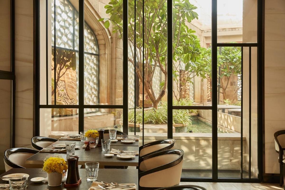 a dining room with a table and chairs and a window at The Taj Mahal Tower, Mumbai in Mumbai a dining room with a table and chairs and a window at The Taj Mahal Tower, Mumbai in Mumbai