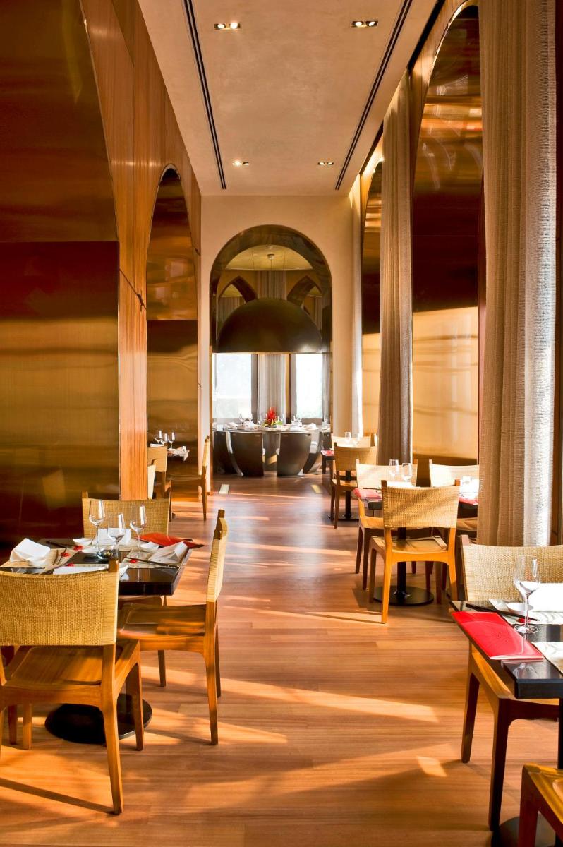 a restaurant with wooden tables and chairs and a large room at The Taj Mahal Tower, Mumbai in Mumbai a restaurant with wooden tables and chairs and a large room at The Taj Mahal Tower, Mumbai in Mumbai
