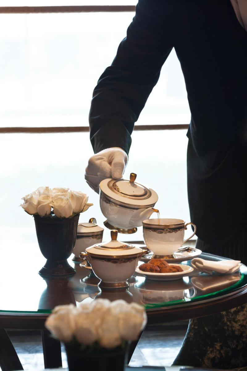 a person holding a tea set on a table with cups at The Taj Mahal Tower, Mumbai in Mumbai a person holding a tea set on a table with cups at The Taj Mahal Tower, Mumbai in Mumbai