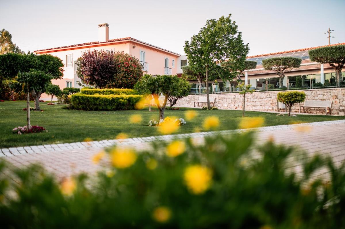 um jardim com flores amarelas em frente a um edifício em Hotel de Charme Casa da Amieira em Amiães de Cima