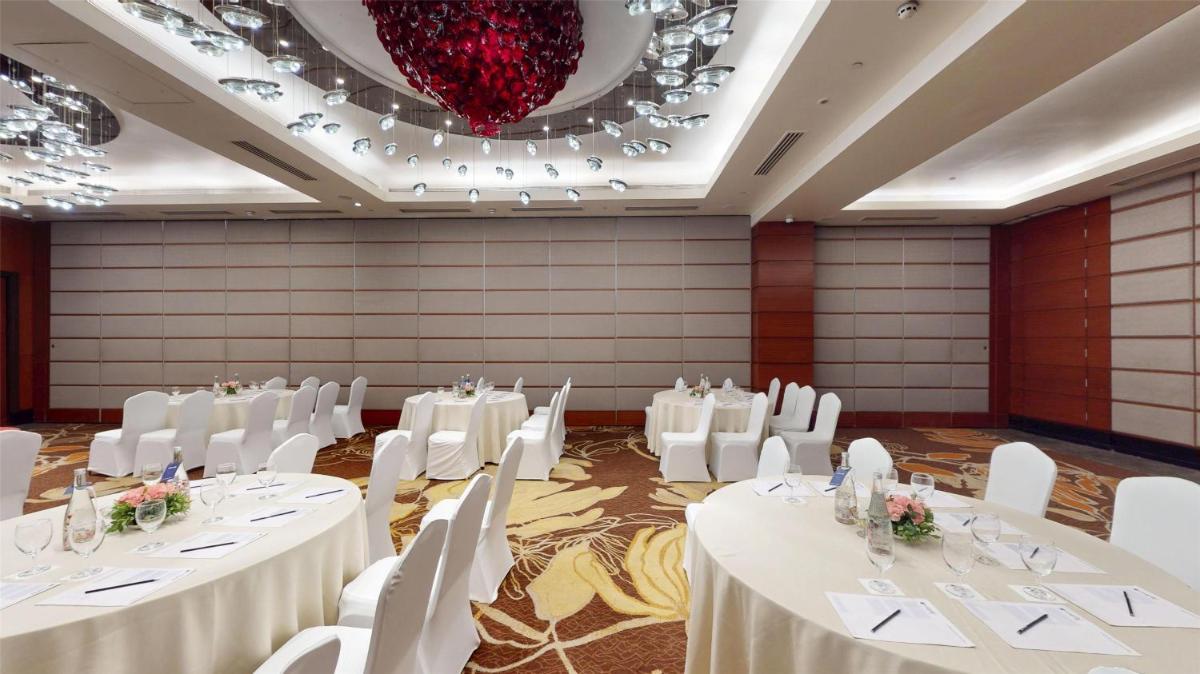 a banquet hall with white tables and chairs and a chandelier at Radisson Blu Hotel, Nagpur in Nagpur