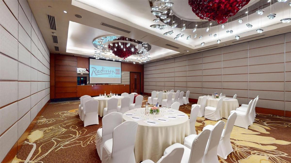 a room with white tables and white chairs and a screen at Radisson Blu Hotel, Nagpur in Nagpur