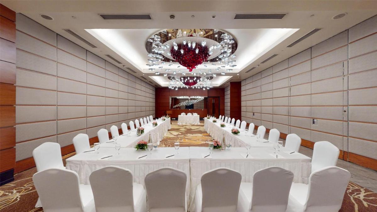 a banquet hall with white tables and chairs and a chandelier at Radisson Blu Hotel, Nagpur in Nagpur