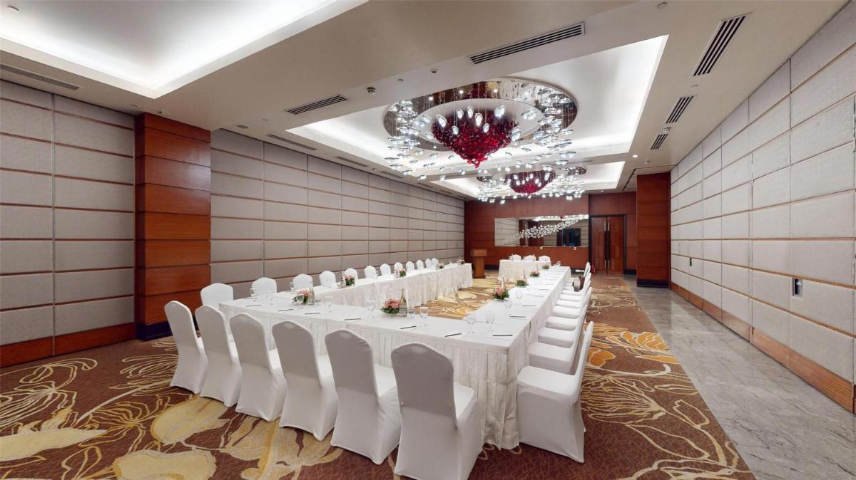 a banquet hall with white tables and white chairs at Radisson Blu Hotel, Nagpur in Nagpur