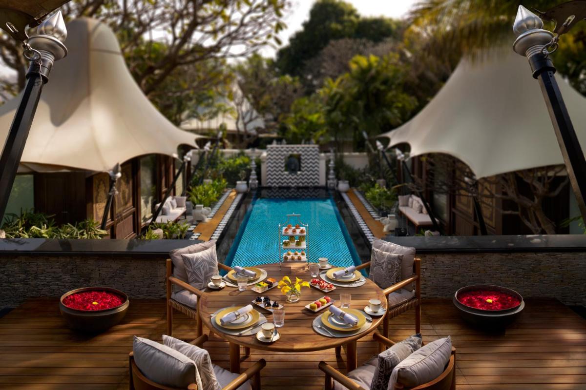 a table and chairs next to a swimming pool at The Leela Palace Udaipur in Udaipur